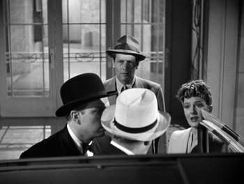 Movie still from “The More the Merrier” (1943), directed by George Stevens – A group of men and women sitting around a piano; Medium shot, Over the shoulder angle