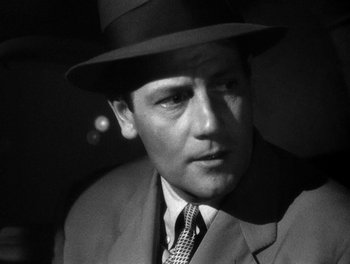Movie still from “The More the Merrier” (1943), directed by George Stevens – A black and white photo of a man wearing a suit and a hat; Close Up shot, Low angle