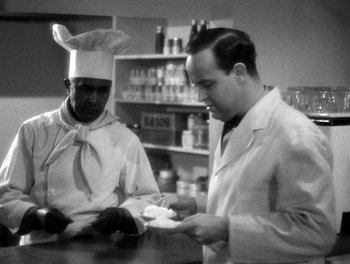 Movie still from “The More the Merrier” (1943), directed by George Stevens – A man in a chef's hat and a man in a lab coat are looking at something; Medium shot, High angle