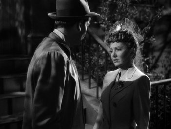 Movie still from “The More the Merrier” (1943), directed by George Stevens – A man and a woman standing next to each other in front of trees; Close Up shot, Over the shoulder angle