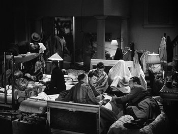Movie still from “The More the Merrier” (1943), directed by George Stevens – A black and white photo of people sitting in a room; Wide shot, High angle