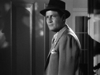 Movie still from “The More the Merrier” (1943), directed by George Stevens – A black and white photo of a man in a suit and hat; Close Up shot, Low angle