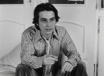 Movie still from “The Mother and the Whore” (1973), directed by Jean Eustache – A man sitting on a couch wearing a tie; Close Up shot, Low angle