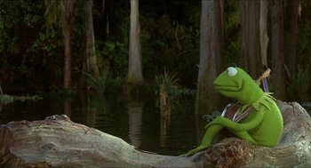 Movie still from “The Muppet Movie” (1979), directed by James Frawley – Kermit the frog sitting on a rock in front of some trees; Medium shot, Over the shoulder angle