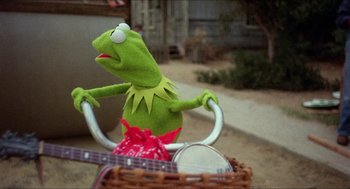 Movie still from “The Muppet Movie” (1979), directed by James Frawley – A green stuffed animal sitting on top of a basket; Close Up shot, Low angle