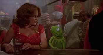 Movie still from “The Muppet Movie” (1979), directed by James Frawley – A woman in a red dress sitting next to a green muppet; Medium shot, Over the shoulder angle