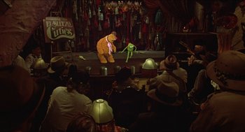 Movie still from “The Muppet Movie” (1979), directed by James Frawley – A crowd of people sitting around a stage with a puppet; Wide shot, High angle