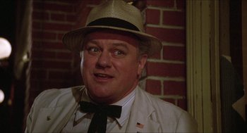 Movie still from “The Muppet Movie” (1979), directed by James Frawley – A person wearing a hat and a tie; Close Up shot, Over the shoulder angle