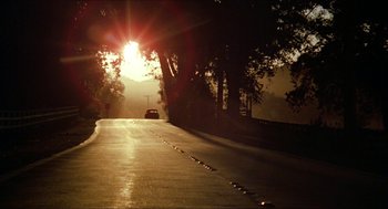 Movie still from “The Muppet Movie” (1979), directed by James Frawley – A car driving down a street near a forest at sunset; Extreme Wide shot, Low angle