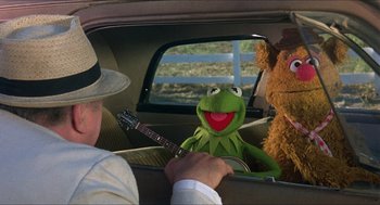 Movie still from “The Muppet Movie” (1979), directed by James Frawley – Kermit the frog and fozzie bear in the backseat of a car; Medium shot, Over the shoulder angle