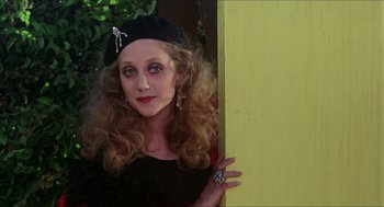 Movie still from “The Muppet Movie” (1979), directed by James Frawley – A woman in a black dress and a black hat is leaning against a yellow wall; Close Up shot, Low angle