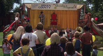 Movie still from “The Muppet Movie” (1979), directed by James Frawley – A crowd of people watching a man on a stage; Wide shot, High angle