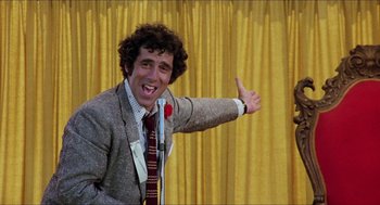 Movie still from “The Muppet Movie” (1979), directed by James Frawley – A man in a suit and tie giving a thumbs up; Medium shot, Low angle