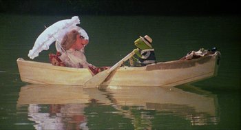 Movie still from “The Muppet Movie” (1979), directed by James Frawley – Kermit and miss piggy are in a boat on a lake; Wide shot, High angle