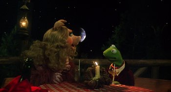 Movie still from “The Muppet Movie” (1979), directed by James Frawley – A couple of stuffed animals sitting next to each other on top of a table; Medium shot, High angle
