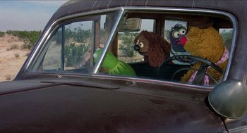 Movie still from “The Muppet Movie” (1979), directed by James Frawley – A stuffed animal sitting in the passenger seat of an old car; Wide shot, High angle