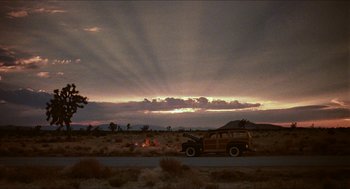 Movie still from “The Muppet Movie” (1979), directed by James Frawley – An old car is parked on the side of the road near a campfire; Extreme Wide shot, Low angle