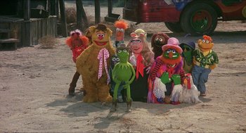Movie still from “The Muppet Movie” (1979), directed by James Frawley – A group of stuffed animals sitting next to each other on the beach; Wide shot, High angle