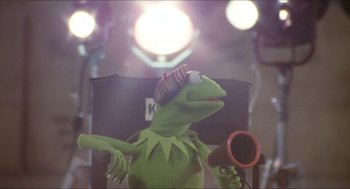 Movie still from “The Muppet Movie” (1979), directed by James Frawley – A kermit the frog sitting in a chair with a hair dryer; Medium shot, Low angle