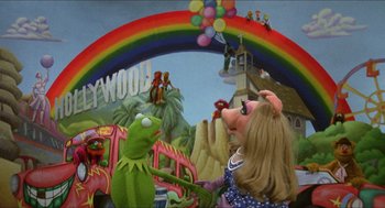 Movie still from “The Muppet Movie” (1979), directed by James Frawley – A rainbow in the background with a muppet and a girl in the foreground; Wide shot, High angle
