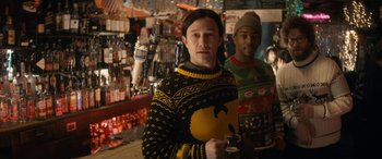 Movie still from “The Night Before” (2015), directed by Jonathan Levine – A man wearing a sweater is standing in a bar; Medium shot, Over the shoulder angle