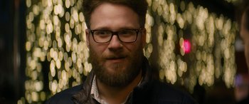 Movie still from “The Night Before” (2015), directed by Jonathan Levine – A person wearing glasses and a jacket; Close Up shot, Over the shoulder angle