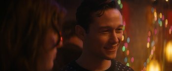 Movie still from “The Night Before” (2015), directed by Jonathan Levine – A young man smiles brightly at a party; Close Up shot, Over the shoulder angle