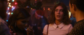 Movie still from “The Night Before” (2015), directed by Jonathan Levine – A woman standing next to a man holding a cell phone; Close Up shot, Over the shoulder angle