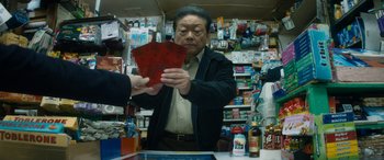 Movie still from “The Night Before” (2015), directed by Jonathan Levine – An older man is holding a red piece of paper in his hand; Medium shot, High angle