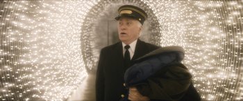 Movie still from “The Night Before” (2015), directed by Jonathan Levine – An older man in a uniform holding an umbrella in front of lights; Medium shot, Over the shoulder angle