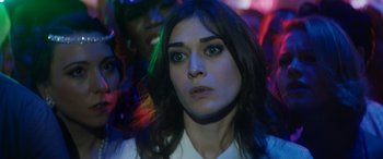 Movie still from “The Night Before” (2015), directed by Jonathan Levine – A person wearing a white shirt with lights in the background; Close Up shot, Over the shoulder angle