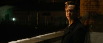 Movie still from “The Night Before” (2015), directed by Jonathan Levine – A man in black shirt standing next to a train track; Close Up shot, Over the shoulder angle