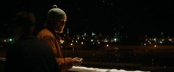 Movie still from “The Night Before” (2015), directed by Jonathan Levine – A person standing in the snow holding a cell phone; Medium shot, Over the shoulder angle