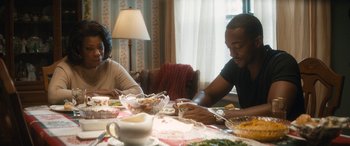 Movie still from “The Night Before” (2015), directed by Jonathan Levine – Two people sitting at a dinner table with plates of food on the table; Medium shot, Over the shoulder angle