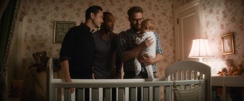 Movie still from “The Night Before” (2015), directed by Jonathan Levine – A group of men standing next to each other holding a baby; Medium shot, Over the shoulder angle