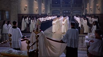 Movie still from “The Nun's Story” (1959), directed by Fred Zinnemann – A group of men in white robes standing next to each other in front of an audience; Extreme Wide shot, High angle