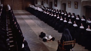 Movie still from “The Nun's Story” (1959), directed by Fred Zinnemann – Many nuns sitting in a row and one nun laying on the floor; Extreme Wide shot, High angle