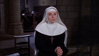Movie still from “The Nun's Story” (1959), directed by Fred Zinnemann – A woman in a nun's outfit holding her hands in prayer; Medium shot, High angle