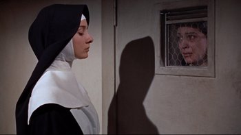 Movie still from “The Nun's Story” (1959), directed by Fred Zinnemann – A woman in a nun's outfit looking at a man in a cage; Close Up shot, Low angle