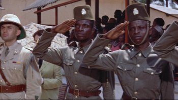 Movie still from “The Nun's Story” (1959), directed by Fred Zinnemann – A couple of men in uniform saluting in front of a group of onlookers; Medium shot, Low angle