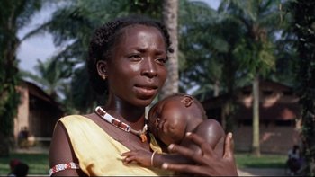 Movie still from “The Nun's Story” (1959), directed by Fred Zinnemann – A woman holding a baby in her arms in front of palm trees; Close Up shot, High angle