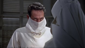 Movie still from “The Nun's Story” (1959), directed by Fred Zinnemann – A man in a white shirt and a white mask; Close Up shot, Over the shoulder angle