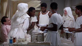 Movie still from “The Nun's Story” (1959), directed by Fred Zinnemann – A group of men in white robes preparing food in a kitchen; Medium shot, High angle