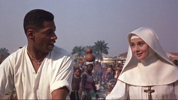 Movie still from “The Nun's Story” (1959), directed by Fred Zinnemann – A man and a woman standing next to each other in front of a crowd; Close Up shot, Low angle