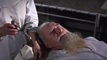 Movie still from “The Nun's Story” (1959), directed by Fred Zinnemann – An old man with a long beard getting a haircut; Close Up shot, Low angle