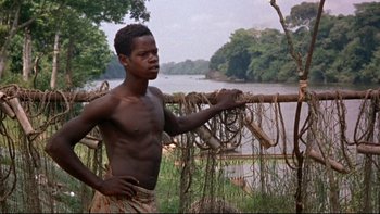 Movie still from “The Nun's Story” (1959), directed by Fred Zinnemann – A man standing in front of a body of water; Medium shot, Low angle
