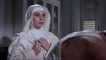 Movie still from “The Nun's Story” (1959), directed by Fred Zinnemann – A woman in a nun's outfit looking at her reflection in a mirror; Close Up shot, Low angle