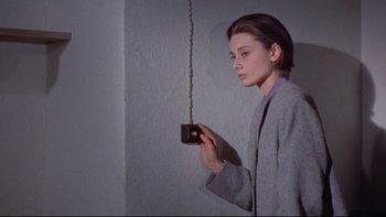 Movie still from “The Nun's Story” (1959), directed by Fred Zinnemann – A woman holding a camera hanging from a chain; Medium shot, Low angle