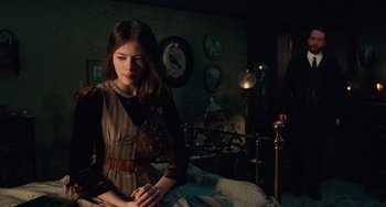 Movie still from “The Nutcracker and the Four Realms” (2018), directed by Joe Johnston – A young woman sitting on a bed in a dark room; Medium shot, Over the shoulder angle