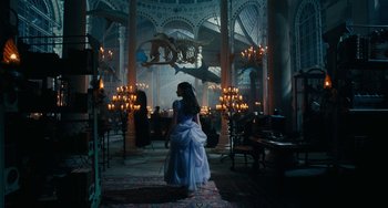 Movie still from “The Nutcracker and the Four Realms” (2018), directed by Joe Johnston – A woman in a blue dress standing in front of a chandelier; Wide shot, High angle